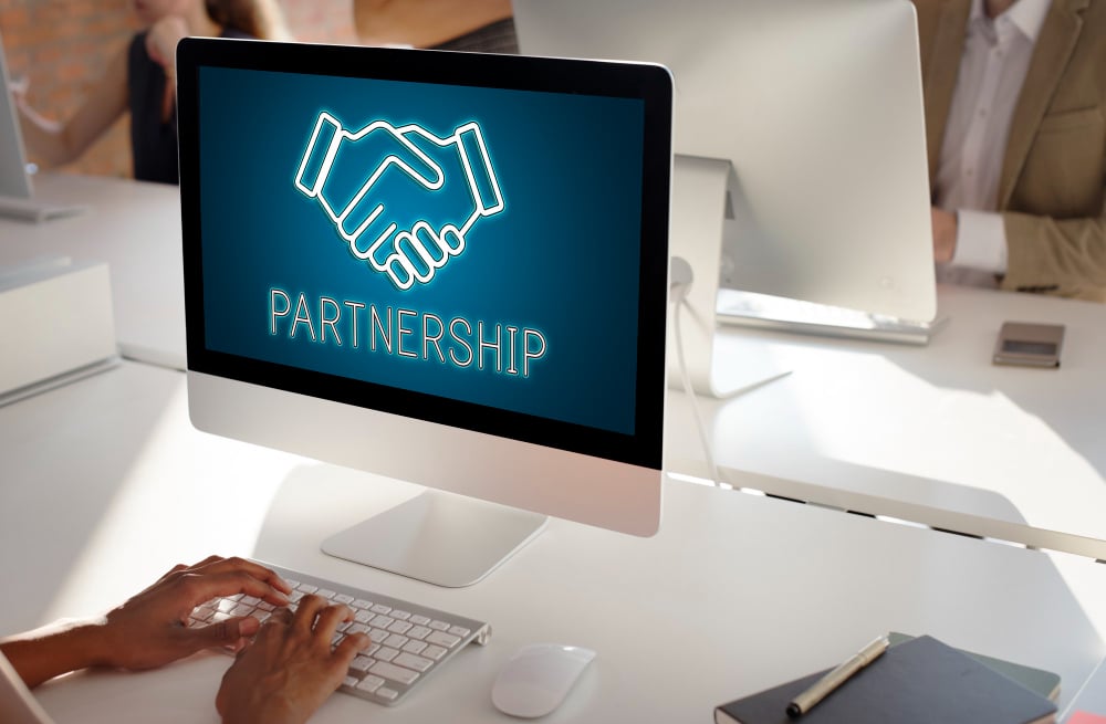 A computer with a handshaking agreement and the word partnership on it.